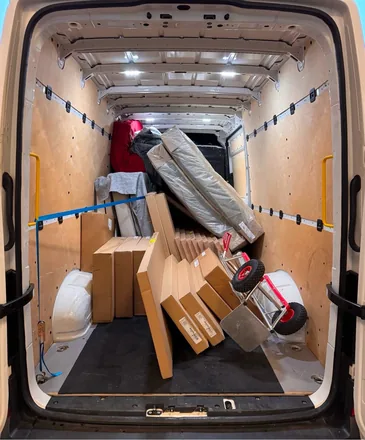 Transporter mit verpackten Möbelpaketen und Sackkarre, mit Spanngurt gesichert