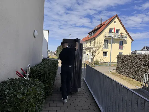 Mitarbeiter trägt einen Schrank zum Umzugswagen